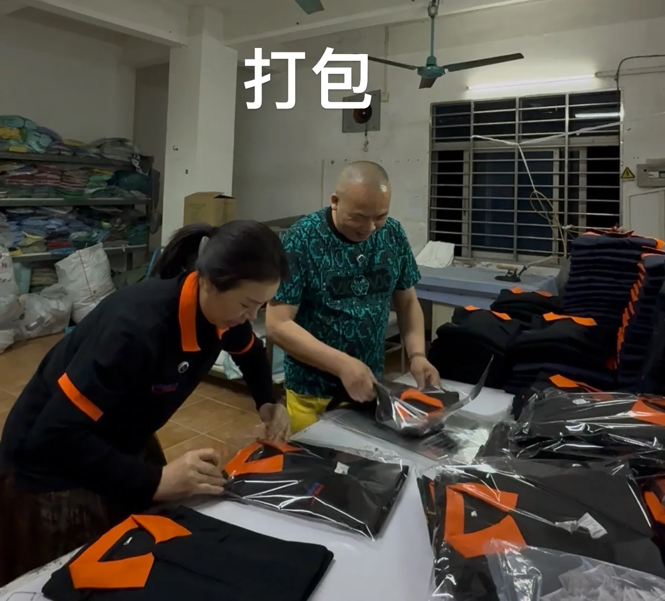 工作人员将黑色橙领 Polo 衫整理装袋
