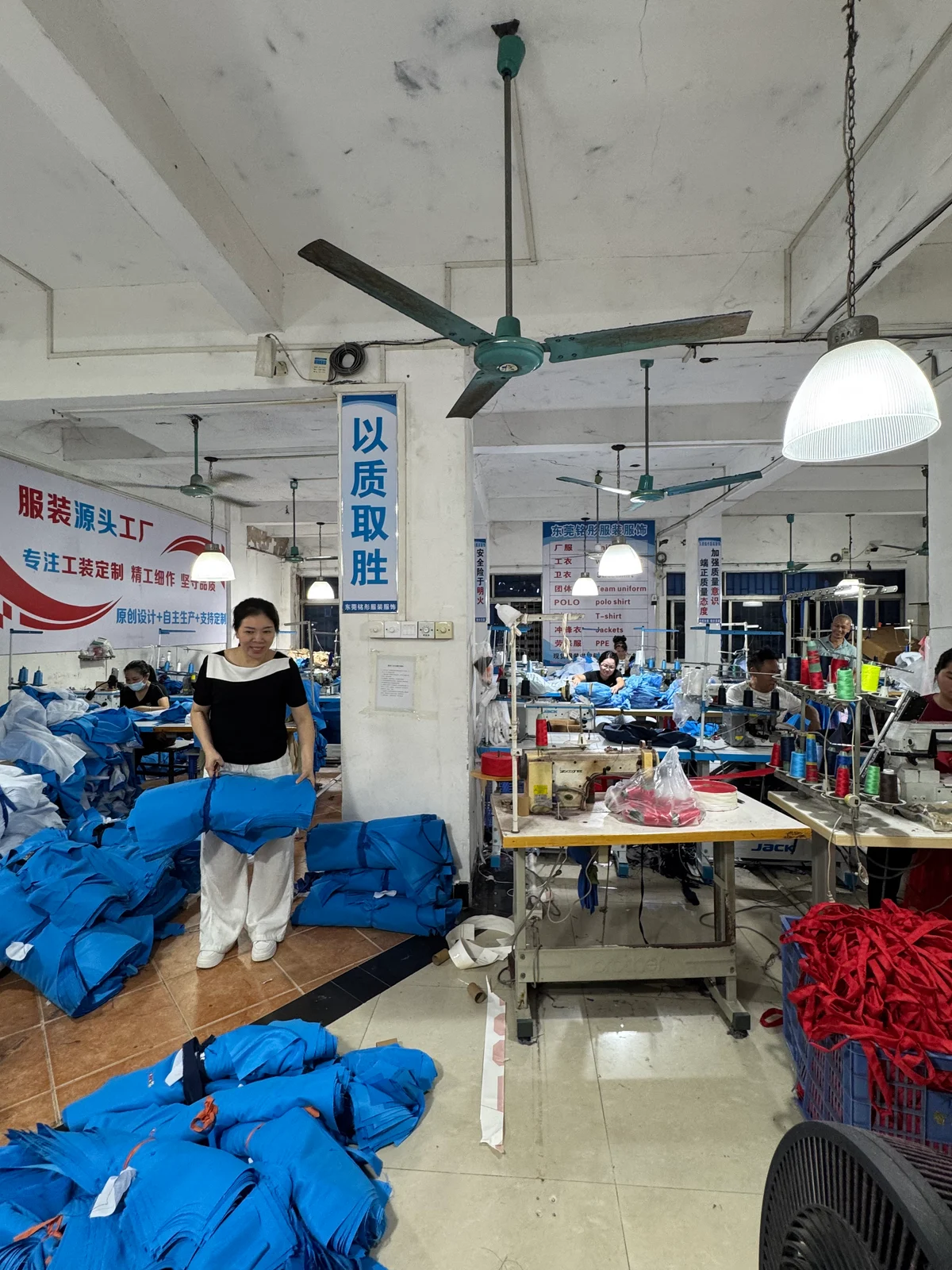 铭彤服装缝制车间,缝纫设备与正在整理的服装
